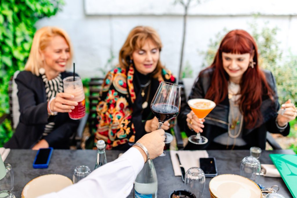 Trei prietene ciocnind pahare cu cocktailuri