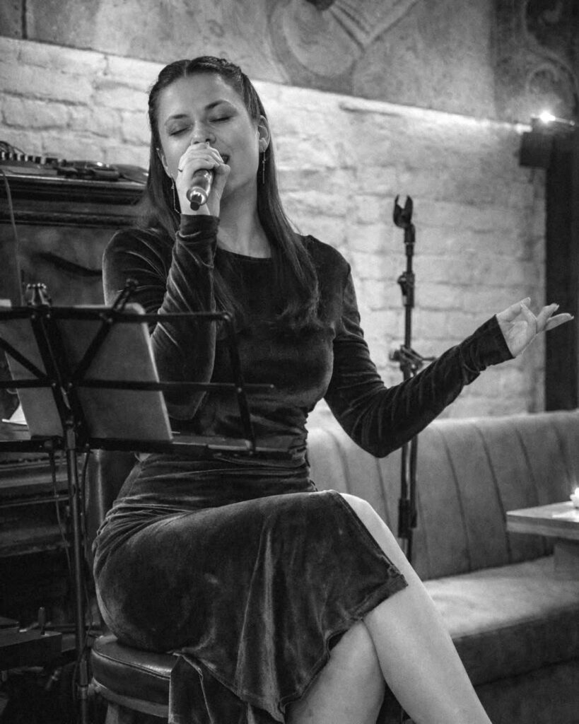 Solista cântând la microfon în sala Brera, fotografie alb-negru