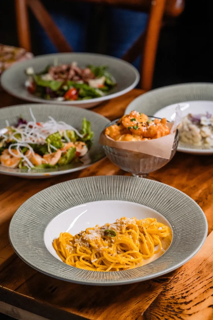 Masă cu salate, creveți și spaghete