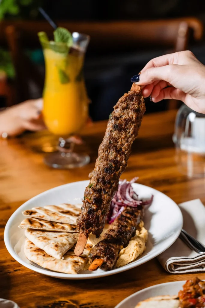 Kebab pe frigăruie, cu lipie și un cocktail alături