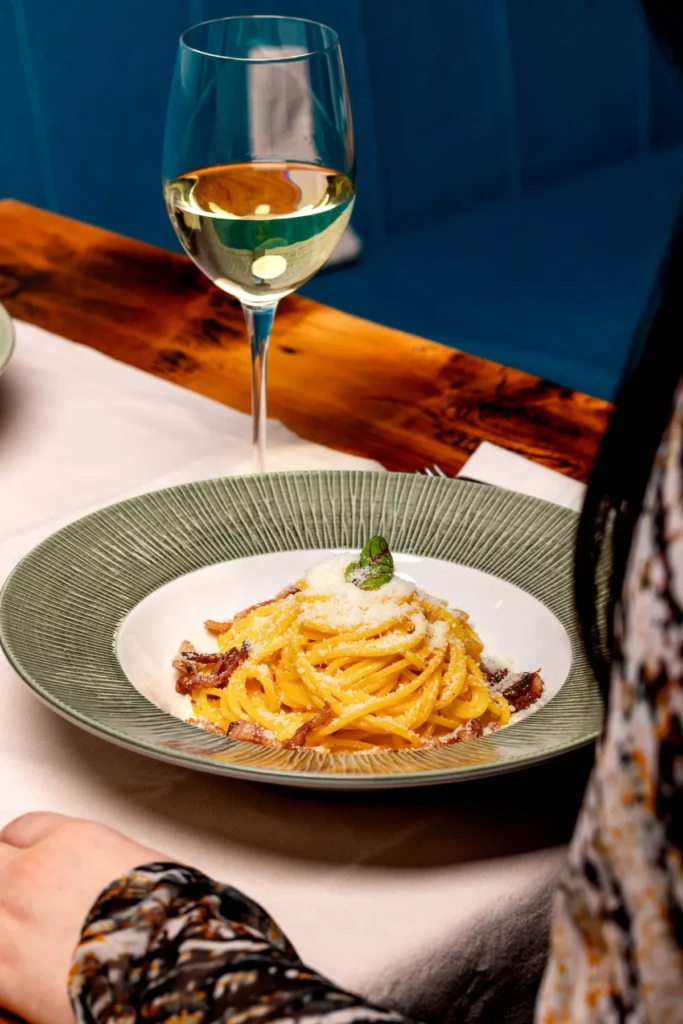 Spaghete carbonara, lângă un pahar de vin alb