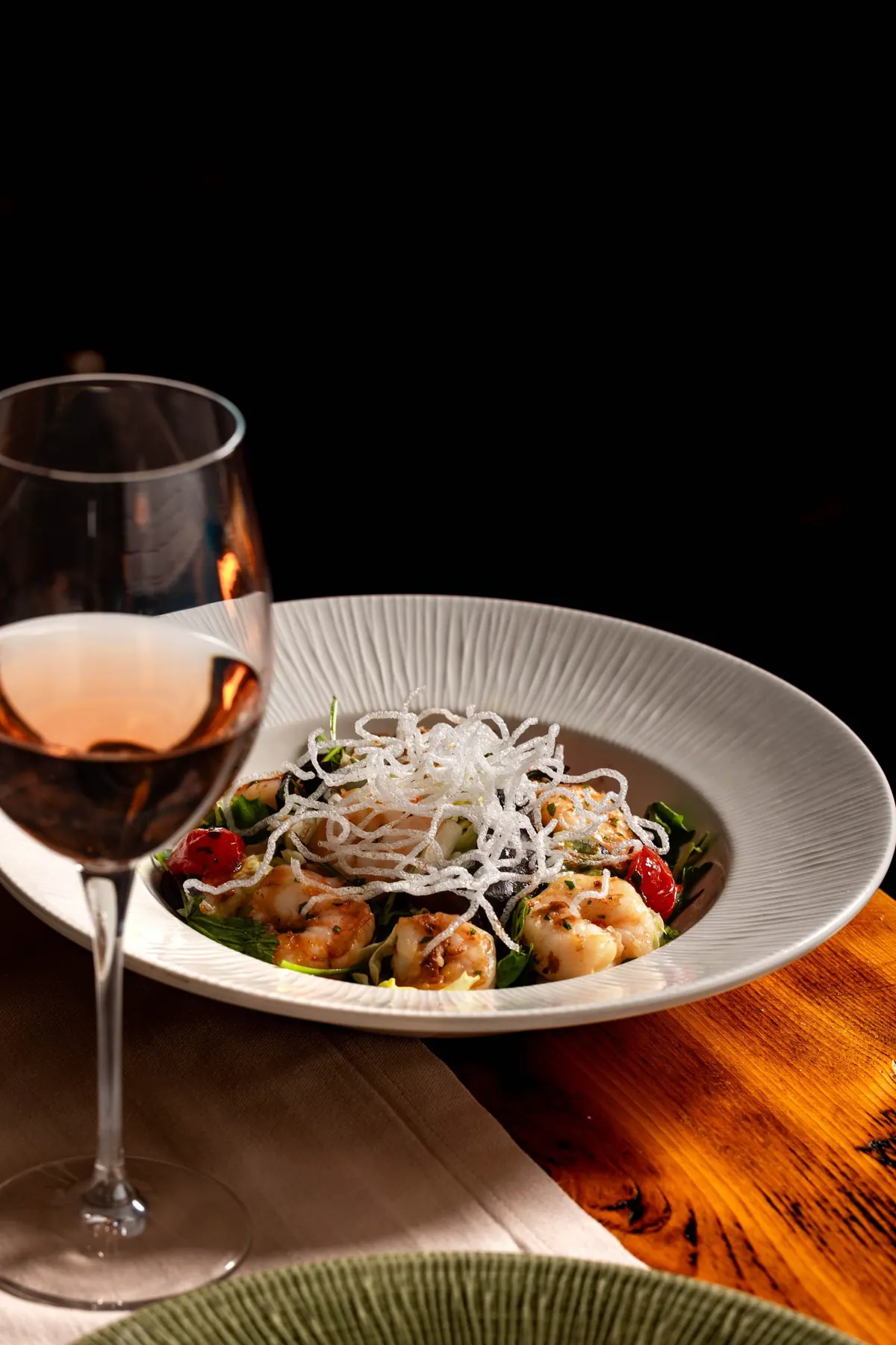 Salată cu creveți, lângă un pahar de vin rosé